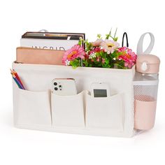 a white bag filled with lots of flowers and office supplies next to a cup on top of a desk