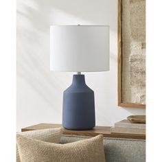 a blue lamp sitting on top of a table next to a pillow and pillows in front of a mirror