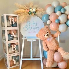 a teddy bear sitting on a chair next to balloons and a sign that says baby shower