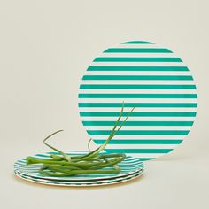 a plate with green beans on it next to a paper plate that has an oval design