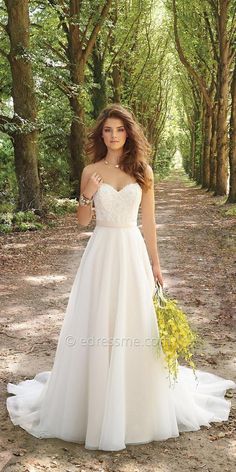 a woman in a white wedding dress holding a yellow bouquet and posing for the camera