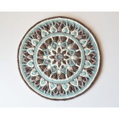 a crocheted doily is hanging on the wall in front of a white wall