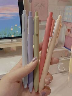 a person holding four different colored pens in their hand and the other one is empty