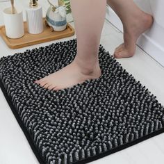 a person is standing on a bath mat in front of a shower with black and white rugs