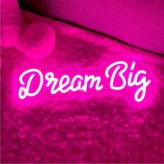 the words dream big are lit up in pink