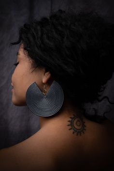 a woman's back with tattoos on her neck and behind her is a black background