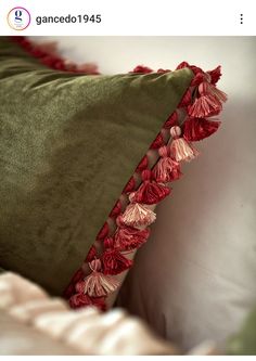 a green pillow with red tassels on it