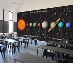 an empty classroom with desks and solar system wall mural