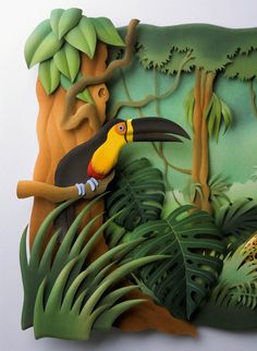 a paper sculpture of a toucan bird on a tree branch in the jungle