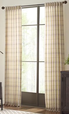 a living room with a chair and large window covered in plaid drapes on the windowsill