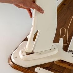 a person is holding the back end of a white computer desk with one hand on it