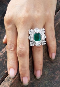 a woman's hand with an emerald and diamond ring