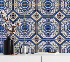 a blue and white tile wall with flowers in a vase on the table next to it