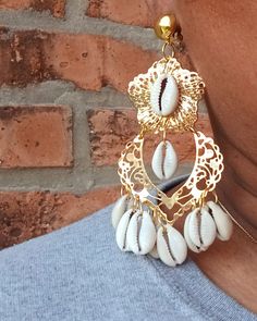 These are unique  Handmade and one of a kind  none other like these   Cowrie shell chandelier style Comfortable Clip on closure  gold metal with hand applied cowrie shells  They hang 3.5 inches  Medium Large sized These are very lightweight on the ear Easy to wear They are one of a kind These Earrings are a classic and timeless addition to any  afrocentric wardrobe Bohemian Gold Shell-shaped Jewelry, Gold Bohemian Shell For Festival, Gold Cowrie Shell Earrings For Gift, Gold Cowrie Shell Earrings As Gift, Bohemian Gold Shell-shaped Earrings, Unique Gold Shell Earrings, Handmade Gold Chandelier Earrings For Summer, Gold Dangle Shell Earrings, Bohemian Gold Chandelier Earrings For Beach