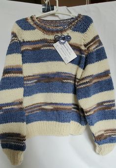 a blue and white striped sweater hanging on a clothes line with a tag attached to it