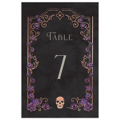 a table number card with a skull and roses on the front, in black paper