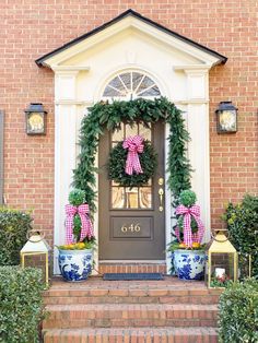 a front door decorated for christmas with wreaths and potted plants