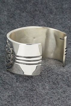 This stunning sterling silver bracelet was made by Navajo silversmith Jerrold Tahe. The inside is signed J. Tahe and stamped sterling.Size: 6" (will fit up to a 7 1/2" wrist)Gap: 1 1/2"Width: 1 1/2"Free shipping on all orders! We ship with USPS and always include tracking. All orders ship within a day of payment.Returns are accepted up to 30 days after you receive your order. Just send us a message. Our shop offers cash back or store credit. The item must be returned in new condition. Southwestern Hallmarked Silver Jewelry, Southwestern Sterling Silver Polished Bangle Bracelet, Southwestern Polished Sterling Silver Bangle, Southwestern Sterling Silver Bangle With Polished Finish, Silver Southwestern Style Bracelet With Oyster Clasp, Sterling Silver Southwestern Bracelet With Polished Finish, Silver Southwestern Style Oyster Bracelet, Southwestern Style Silver Oyster Bracelet, Southwestern Silver Cuff Bracelet With Oyster Detail