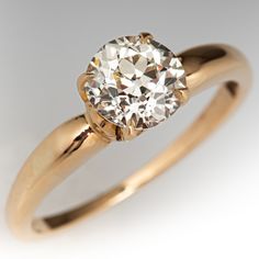 a yellow gold engagement ring with a round diamond in the center, on a white background