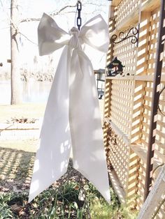 a white bow hanging from the side of a wooden fence