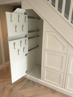 an under stair storage unit in a house with white painted walls and wood flooring