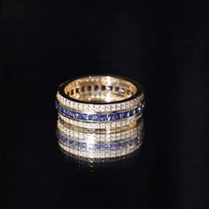 a gold ring with blue and white stones on it's sides, against a black background