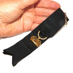 An Edwardian black ribbon watch fob with a tested 14 K ornate seal. The ribbon is folded over and sewn onto a gold-filled hanger which is attached to a gold-filled watch hook via a short chain. The gold seal is hanging on a hollow ring sewn into the fold of the ribbon. The ornate seal has a scrolled top and engraved initials on the bottom -EAC. Everything is in excellent condition. The total length of the fob, from the hook to the end of the ribbon is 18 cm. The seal itself is 2.6 cm wide. A good accessory for the collector of antique watches! Gold Ribbon Jewelry For Formal Occasions, Classic Formal Jewelry With Brass Hardware, Black Jewelry With Gold Clasp For Formal Occasions, Formal Black Jewelry With Black Ribbon, Elegant Gold Jewelry For Black Tie Event, Elegant Gold Jewelry For Black Tie, Elegant Black Jewelry With Gold Clasp, Hollow Ring, Lansing Mi