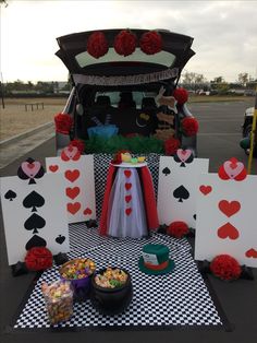 a table with cards and candy on it in front of a car decorated for a party