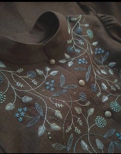 a brown shirt with blue flowers and leaves embroidered on the chest, along with buttons