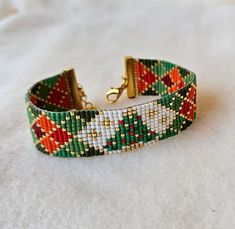 a close up of a beaded bracelet on a white surface with a gold clasp