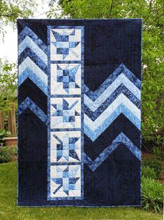 a blue and white chevroned quilt on grass