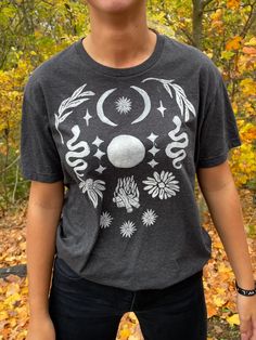 A secondhand T-Shirt with a block-printed design! This Full Moon Design was created with ceremony in mind - wear this shirt near the full moon or when you need some extra full moon energy in your daily life (or if you just want to look very cute with very little effort). This design is offered in other sizes and colors - please see my Etsy page for more offerings! My mission is to bring sacred ceremony into daily life. By curating secondhand clothes and adding symbolism with intention, I hope to spread some love of nature, the Divine, and simple beauty back into all our lives. Each piece I offer was thrifted and chosen with care, lovingly block-printed with hand-carved stamps, and shared with you in community.  My process usually goes a little something like this: Inspiration from nature, Bohemian Cotton T-shirt With Sun And Moon Design, Festival T-shirt With Screen Print And Relaxed Fit, Mystical Cotton Crew Neck T-shirt, Cotton Graphic Tee With Moon Print, Bohemian Short Sleeve T-shirt With Sun And Moon Design, Mystical Crew Neck Cotton T-shirt, Mystical Style Cotton T-shirt With Crew Neck, Mystical Style Cotton Crew Neck T-shirt, Bohemian Cotton Tops With Sun And Moon Design