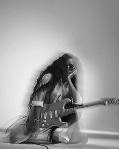 a woman sitting on the floor with a guitar