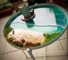 a coffee cup is sitting on top of a table with a view of the beach