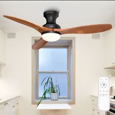 a ceiling fan in a kitchen next to a window with a plant on the counter