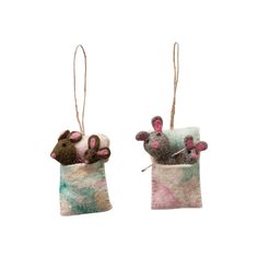 two felt ornaments with mice in them hanging from twine strings on white background, one is pink and the other is green