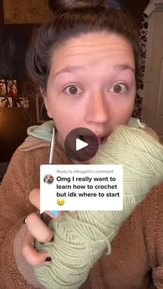 a woman is holding a crochet ball in her hand and looking at the camera