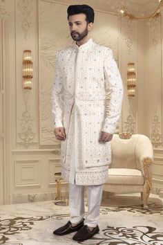 This groom's sherwani, U2-S336, features intricate thread and red accents, as well as sparkling stones. With this traditional and stylish design, the groom will make a statement on his special day. The perfect combination of cultural heritage and contemporary style, The overlapping layers create a unique texture. Embroidered Sherwani For Groom In Transitional Season, Transitional Embroidered Sherwani For Groom, Bollywood Embroidered Sherwani For Groom, Traditional Nehru Jacket With Intricate Embroidery For Groom, Bollywood Sherwani With Intricate Embroidery For Groom, Embroidered Sherwani For Groom, Eid Traditional Wear With Stone Work, Formal Festive Sets With Stone Work, Transitional Season Fitted Sherwani For Groom