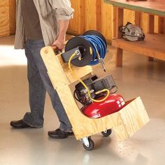 a man is holding a small cart with various items on it and attached to the wheels