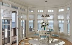 a dining room table and chairs in front of large windows with ocean view behind them