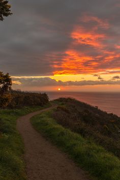 the sun is setting over the ocean and there is a path going up to it