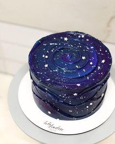 a blue cake with stars on it sitting on top of a white platter in front of a wall