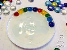 a white plate topped with lots of colorful glass balls