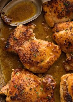 some chicken is cooking in a skillet with sauce on the side and spoons