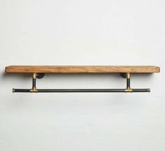 a wooden shelf with two metal bars on it's sides and a white wall in the background