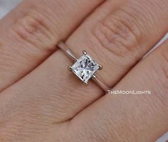 a woman's hand with a white diamond ring on her finger and an engagement band