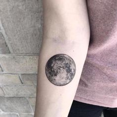 a woman's arm with a tattoo on it and the moon in the background