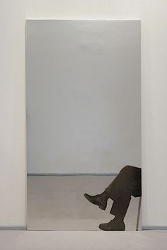 a person sitting on a chair in front of a white wall with an open doorway