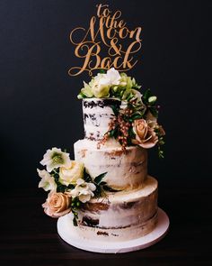 a wedding cake with flowers and the words mr and mrs back on top is sitting on a table