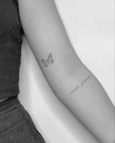 a woman's arm with a small butterfly tattoo on the left side of her arm